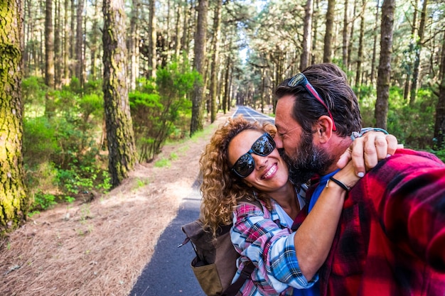 Gente feliz pareja caucásica disfrutando de la actividad de ocio al aire libre juntos viajando en un bosque en una larga carretera asfaltada