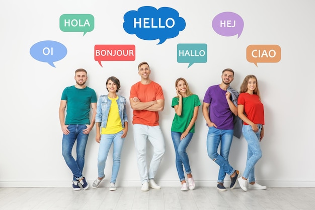 Foto gente feliz posando cerca de la pared de luz e ilustración de burbujas de habla con la palabra hola escrita en diferentes idiomas