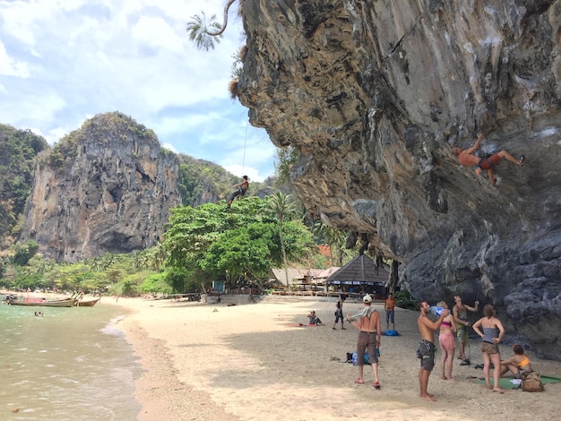 Foto gente por formación rocosa en la playa