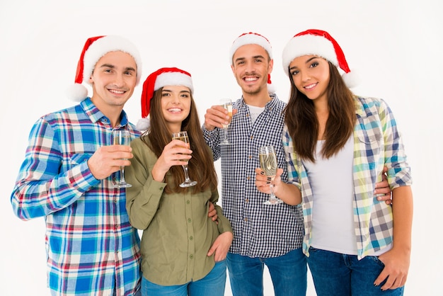 Gente guapa con gorros de santa celebrando la Navidad con champán