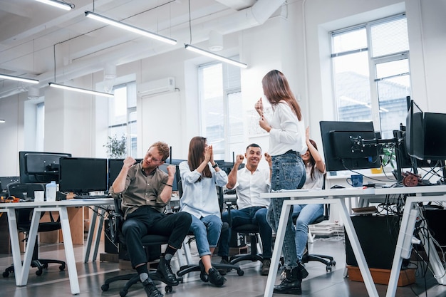 Gente hablando y trabajando juntos en la oficina moderna cerca de las computadoras.