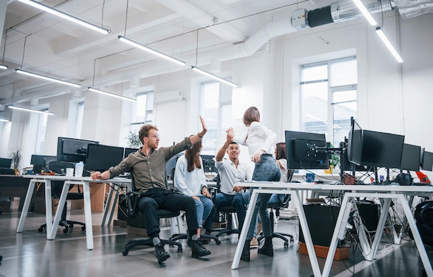 Foto gente hablando y trabajando juntos en la oficina moderna cerca de las computadoras.