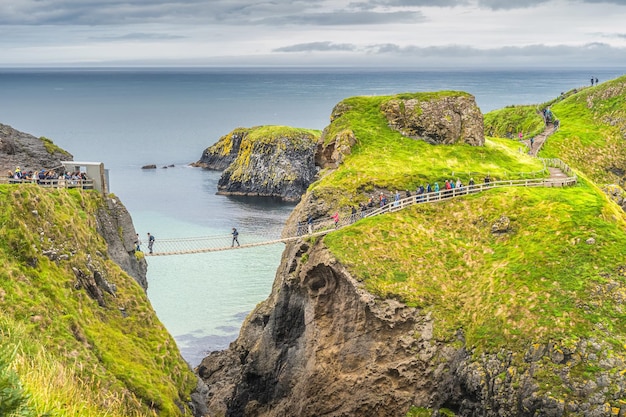 Foto la gente hace cola para cruzar carrick, un puente de cuerda para acceder a la isla de irlanda del norte.