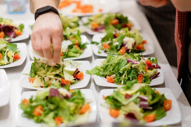 Gente haciendo ensalada juntos Un hombre agrega especias a la ensalada Concepto de comida saludable para cocinar en casa