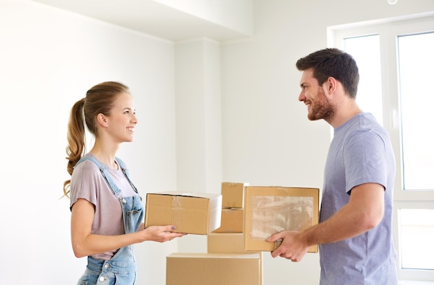 la gente de la hipoteca y el concepto de bienes raíces pareja feliz con cajas mudándose a una nueva casa