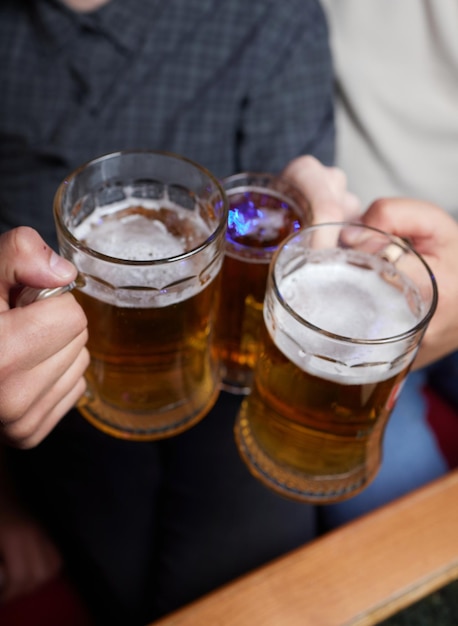 Gente hombres ocio amistad y concepto de celebración felices amigos varones bebiendo cerveza y tintineando vasos en el bar o pub