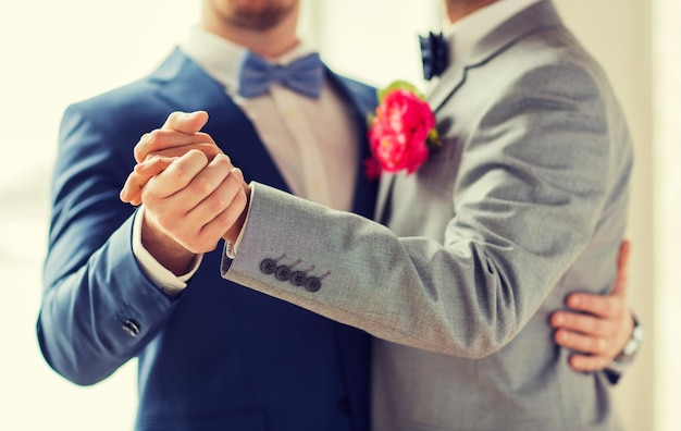 gente, homosexualidad, matrimonio entre personas del mismo sexo y concepto de amor - cerca de una feliz pareja gay masculina tomándose de la mano y bailando en la boda