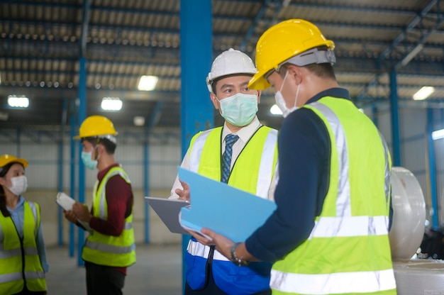 La gente del ingeniero lleva una máscara protectora que trabaja en el almacén