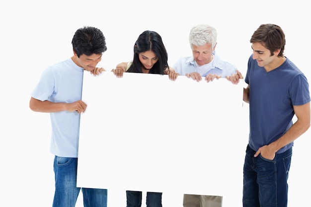 Gente en jeans sosteniendo y mirando un gran cartel