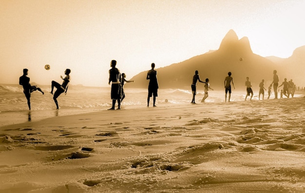 Gente jugando al fútbol en la playa contra un cielo despejado
