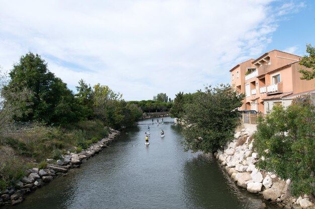 Foto gente junto al río en medio de árboles y edificios contra el cielo