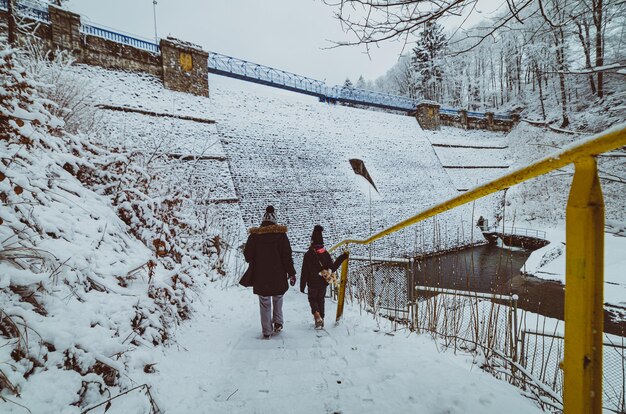 Gente junto a la presa cubierta de nieve