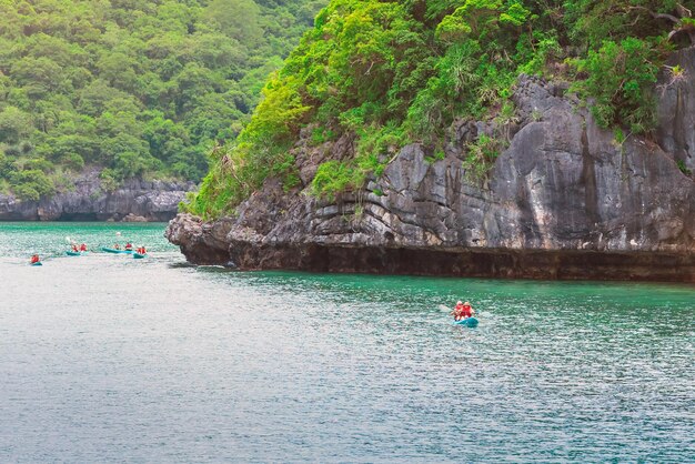 La gente en kayak en el mar contra la roca