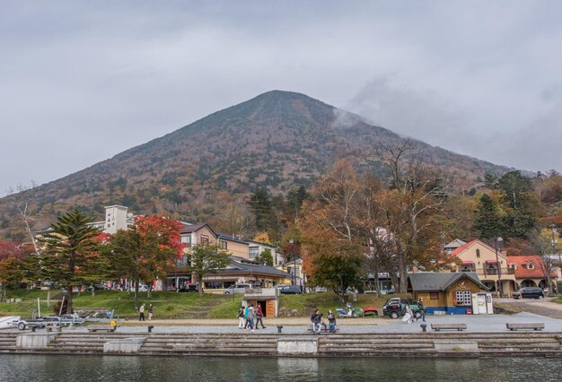 Foto la gente en el lago chuzenji por la montaña contra el cielo despejado