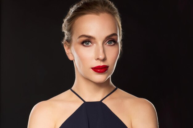 gente, lujo y concepto de moda - hermosa mujer de negro con labios rojos sobre fondo oscuro