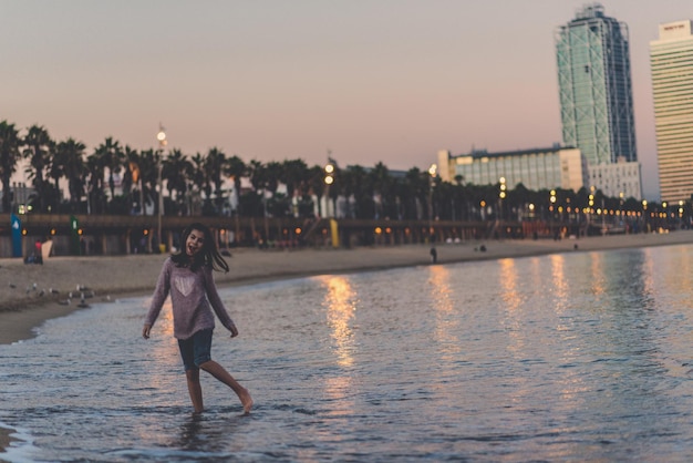Gente en el mar por ciudad contra el cielo durante la puesta de sol
