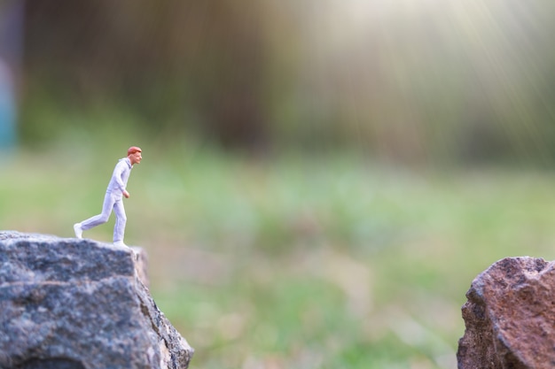 Gente en miniatura: corriendo en un acantilado de roca con fondo de naturaleza