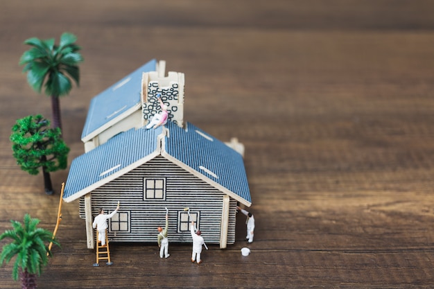 Gente en miniatura: equipo de trabajadores pintando un nuevo hogar.