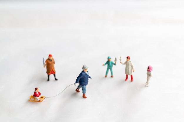 Gente en miniatura Familia feliz monta un trineo con fondo de nieve