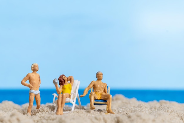 Gente en miniatura Familia feliz relajándose en la playa