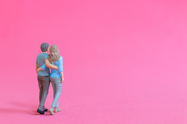 Gente en miniatura hombre y mujer en ropa casual de pie juntos sobre fondo rosa