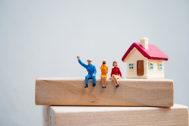 Gente miniatura, hombre y mujer sentada en bloque de madera usando como negocio y concepto social