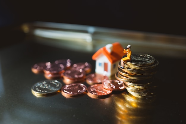 Gente miniatura, hombre que trabaja en monedas de pila de oro usando como negocio y concepto financiero - Vintag