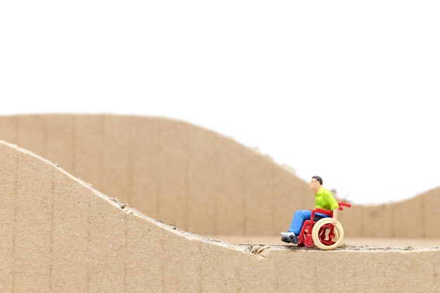 Gente miniatura Hombre en silla de ruedas