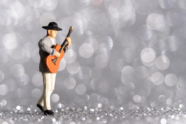 Gente en miniatura Músico con guitarra sobre fondo bokeh