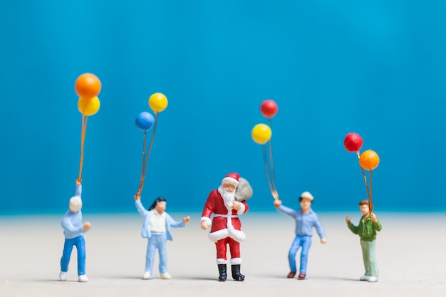 Gente en miniatura: Papá Noel y niños con globo.