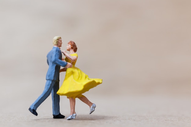 Gente miniatura, pareja bailando sobre fondo de madera