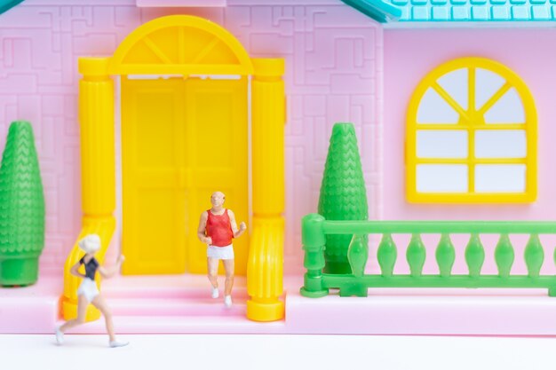 Gente en miniatura, pareja corriendo cerca de su casa juntos, concepto de estilo de vida saludable