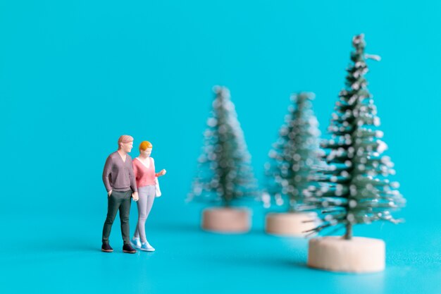 Gente en miniatura, pareja de enamorados de pie junto a un árbol de Navidad, concepto de Navidad y feliz año nuevo.