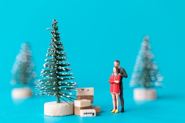 Gente en miniatura, pareja de enamorados de pie junto a un árbol de Navidad, concepto de Navidad y feliz año nuevo.