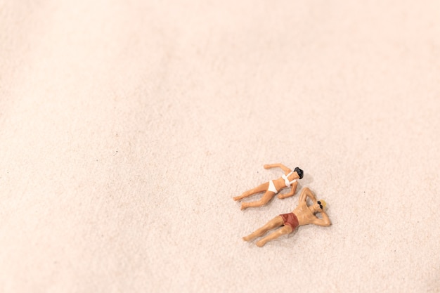 Gente en miniatura, pareja tomando el sol juntos en la playa