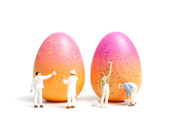 Gente en miniatura pintando huevos de pascua