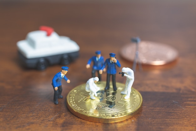 Gente en miniatura: Policía y detective de pie frente a Cryptocurrency bitcoin