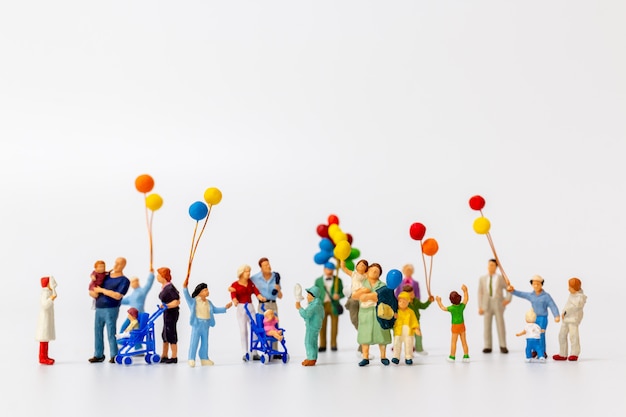 Gente miniatura que sostiene el globo aislado en blanco