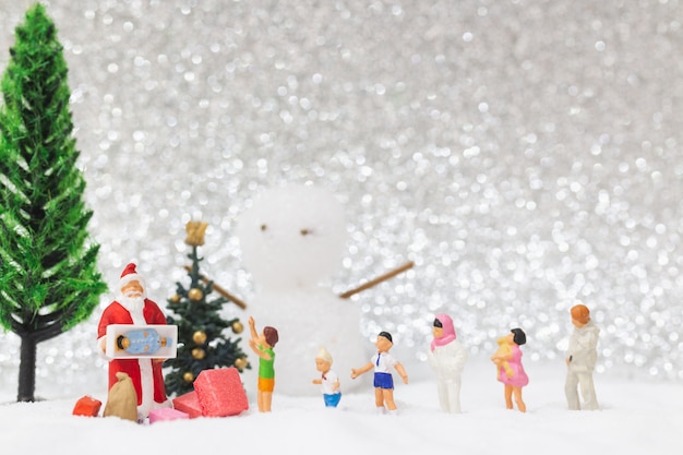 Gente en miniatura: Santa Claus y niños con fondo de nieve