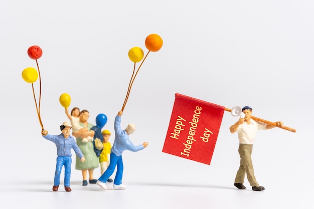 Gente en miniatura sosteniendo banderas con la palabra Feliz Día de la Independencia