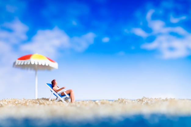 Gente miniatura tomando el sol en la playa, el concepto de horario de verano