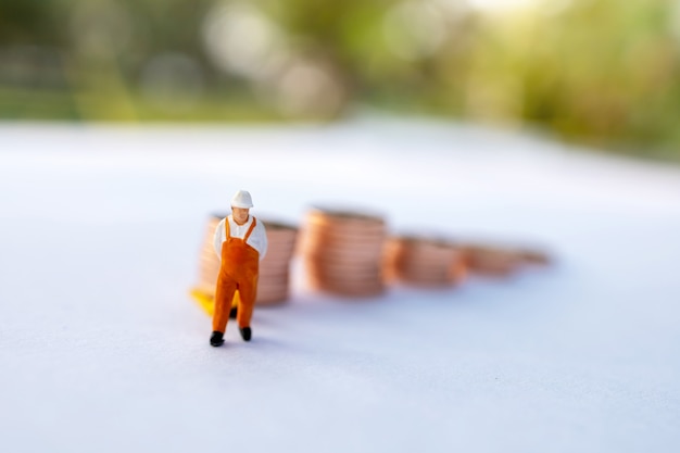 Foto gente en miniatura: trabajador cargando monedas al camión contenedor. envío y concepto de servicio de entrega en línea.