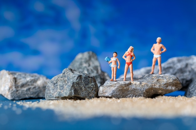 Gente en miniatura con traje de baño relajante en la playa