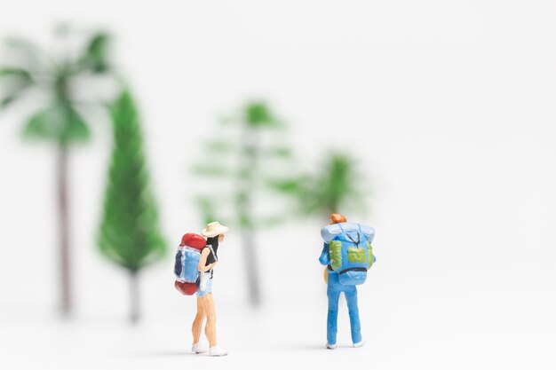 Gente en miniatura: Viajero con mochila caminando en fondo blanco,