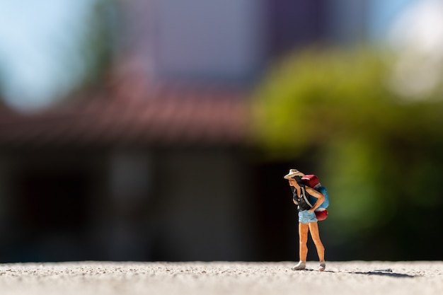 Gente en miniatura: viajero con mochila de pie en el camino