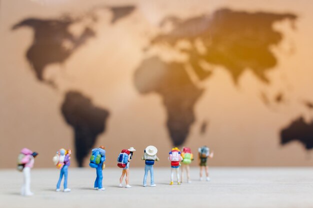 Foto gente en miniatura viajeros caminando por el mapa del mundo