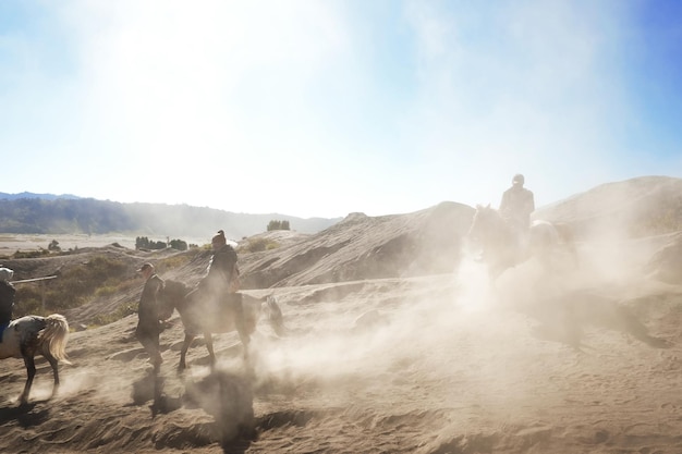 Gente montando caballos en la arena contra el cielo