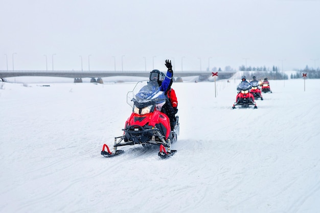 Gente montando motos de nieve y agitando las manos en el lago congelado en invierno Rovaniemi en Laponia, Finlandia