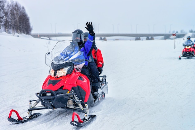 Gente montando motos de nieve y agitando las manos en el lago congelado en invierno Rovaniemi, Laponia, Finlandia