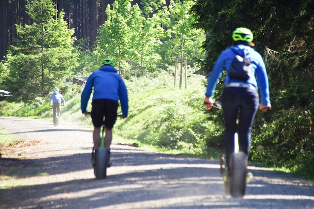 Foto gente montando scooters de empuje en el sendero contra los árboles